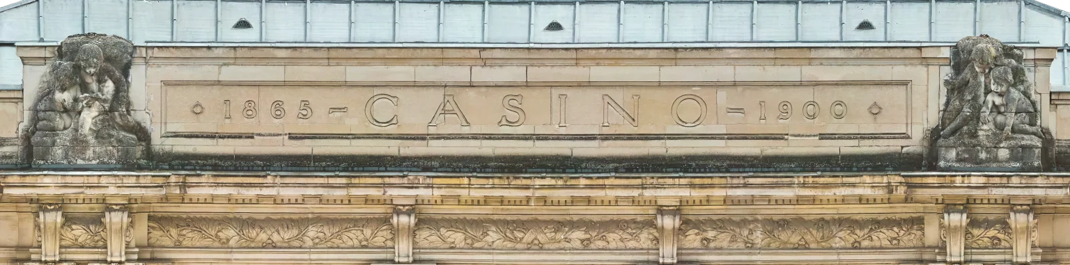 Texte alternatif : Partie haute de la façade du Casino de Vichy, avec l’inscription Casino et les sculptures.